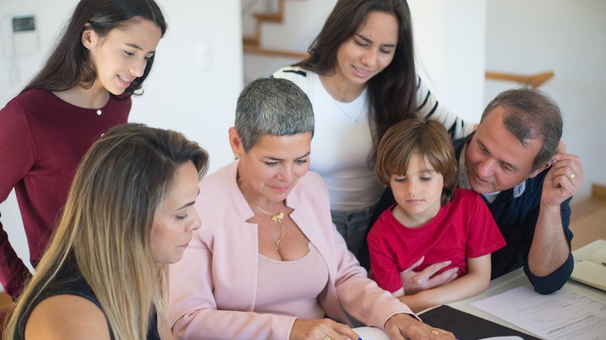 A family discusses real estate documents at home with a realtor, fostering communication and planning.